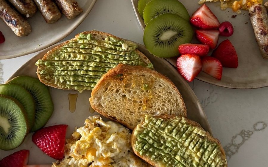 Eggs, sourdough with avocado, sausage and fruit